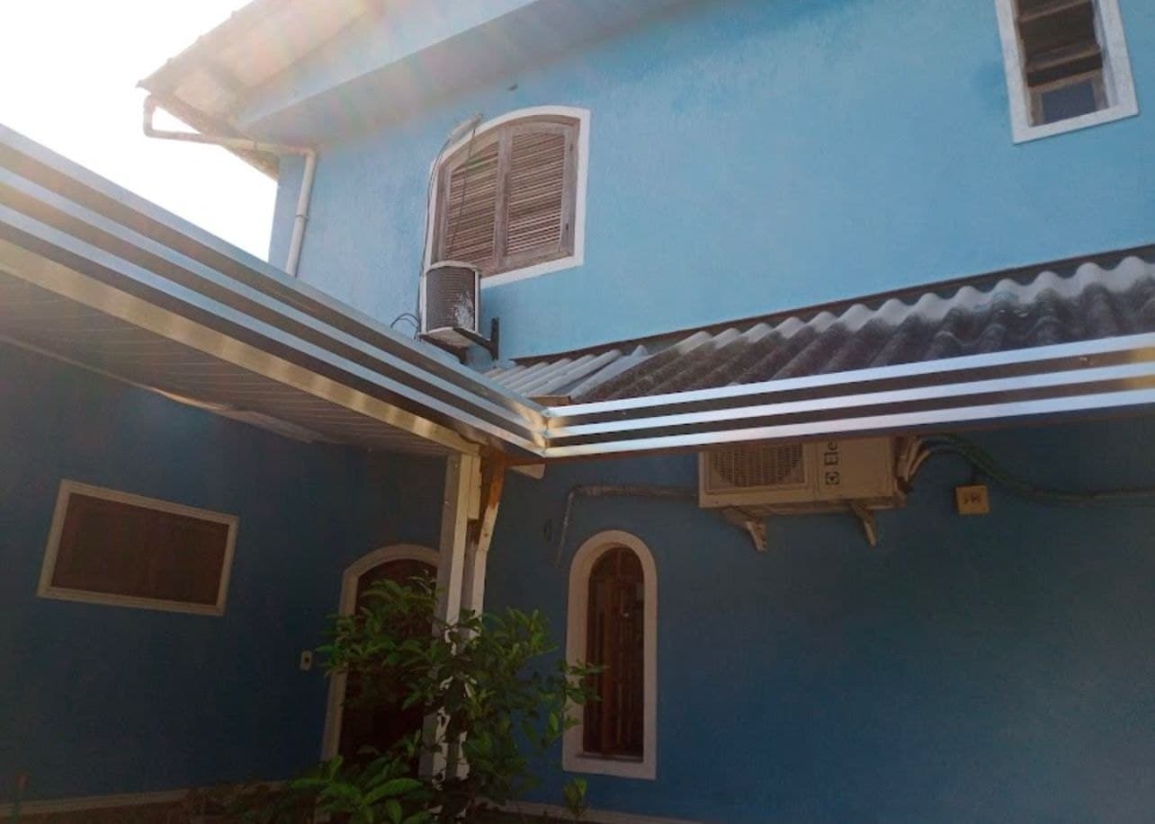 Calha e rufo em alumínio instalados no beiral de uma casa azul