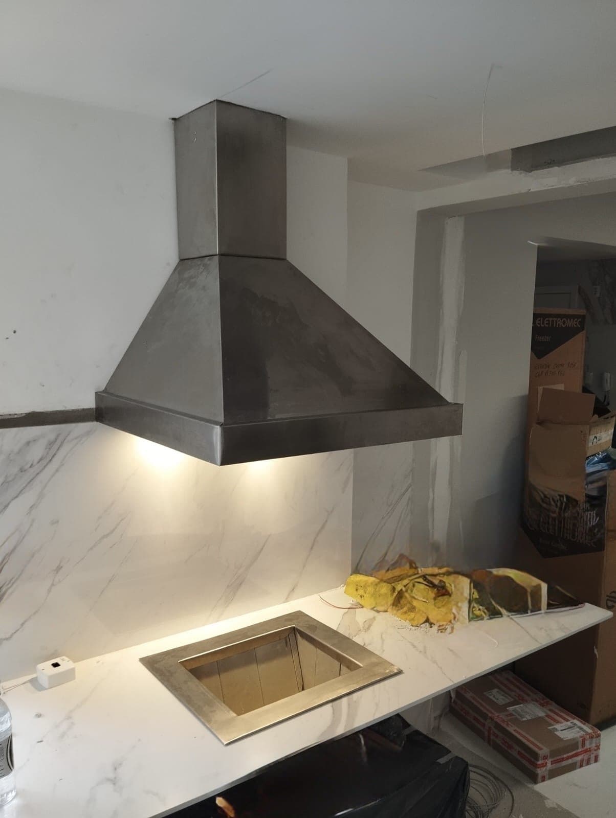 Coifa de parede em inox iluminando uma bancada de mármore