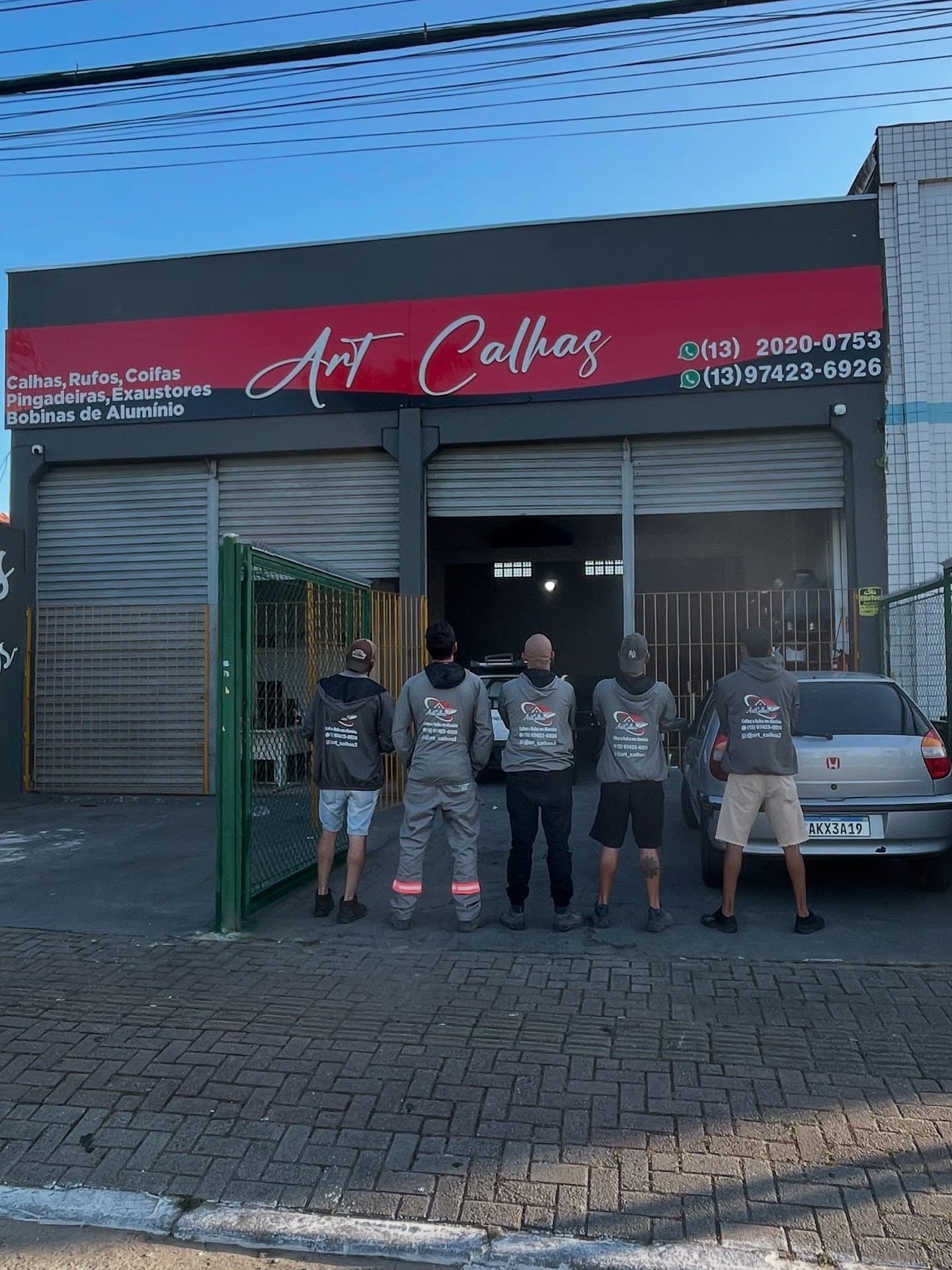 A equipe da Art Calhas, de costas, em frente à loja na Av. Ministro Marcos Freire